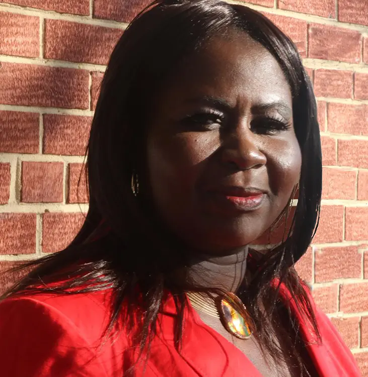 A woman in red is standing against the wall