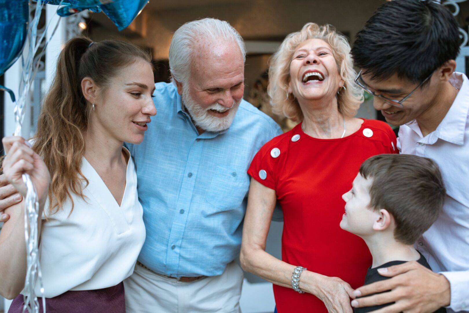 A group of people laughing together with one man holding his hands up to the side.